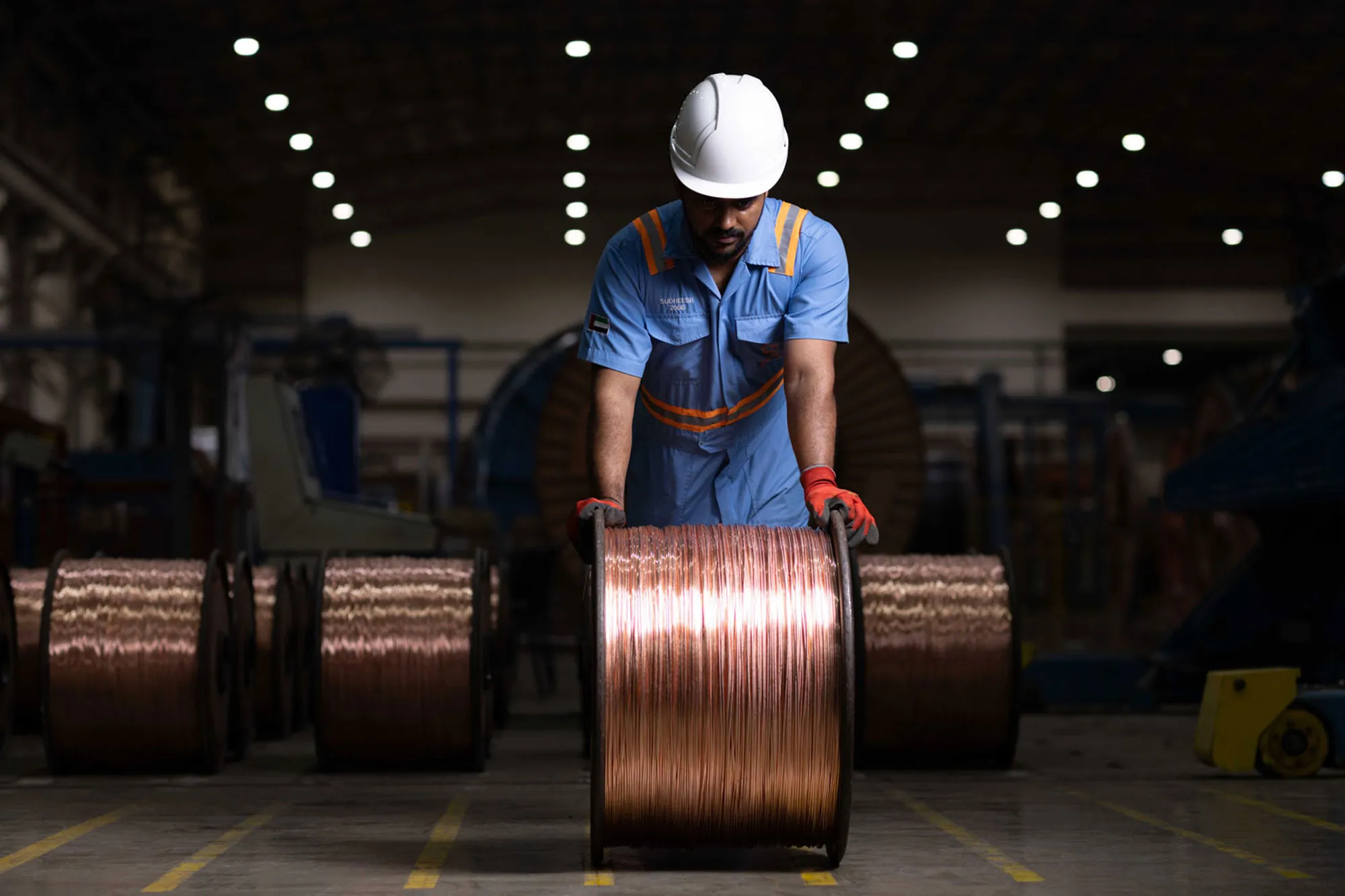 Ducab worker handling a large spool of copper wire